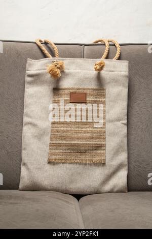 Jute wick tote bag placed on grey sofa, Eco-friendly Beige, Design Template for Mock-up. Front View Stock Photo