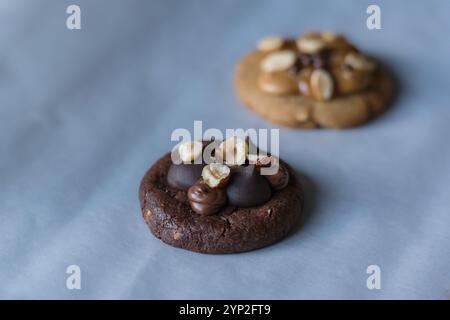 Homemade american dark chocolate cookie with chocolate cream and hazelnut topping with peanut butter cookie on background. Stock Photo