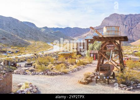 A desert scene with a building that says "Hammer and Nails" on it. The scene is desolate and barren, with a few cars parked in the distance Stock Photo