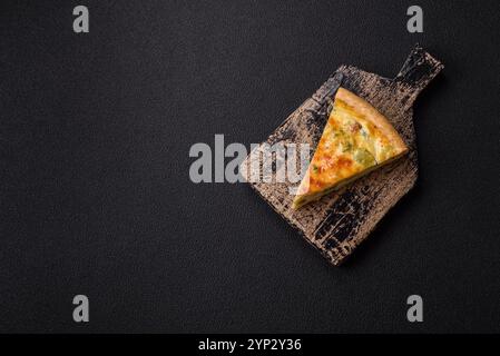 Delicious quiche with broccoli, cheese, chicken, spices and herbs on a dark concrete background Stock Photo