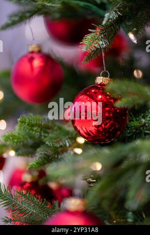 Green artificial fir branches decorated with red balls with garland lights. Stock Photo