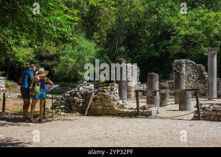 Sarande, Albania - June 7th 2024. Tourists read an information board at the Baptistry Complex in Butrint Archaeological Park, Butrint National Park Stock Photo