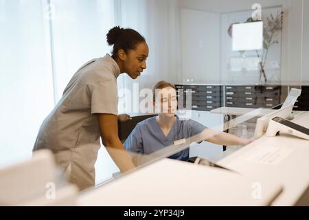 Female healthcare experts discussing over computer while working at hospital Stock Photo