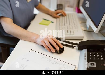 Midsection of female receptionist scrolling mouse while working at desk in hospital Stock Photo