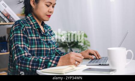 Asian woman working in home or small office with using a laptop. Close up shot hands of freelancer use laptop working on desk of her this is a lifesty Stock Photo
