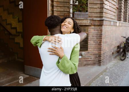 Happy young woman embracing boyfriend while standing near building Stock Photo