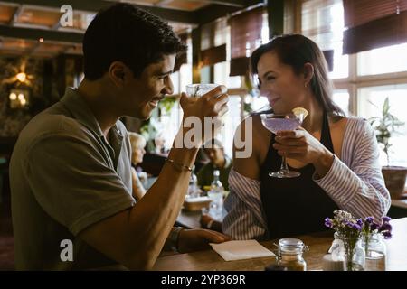 Smiling couple toasting drinks while sitting at bar counter in restaurant Stock Photo