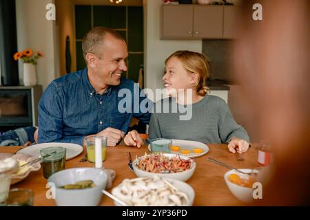 Happy father and son sitting near dining table for lunch at home Stock Photo