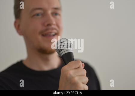 A man singing with microphone. Blurred image with focus on a hand foreground. Stock Photo