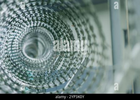 A close-up of a razor wire coil, creating an abstract geometric pattern. The intricate design of the sharp blades forms a visually striking image, per Stock Photo