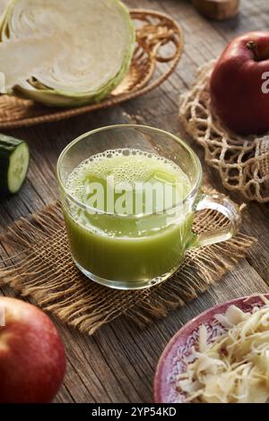 A cup of green cabbage juice with cucumber and apples on a wooden table Stock Photo