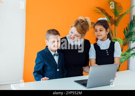 Teacher and boy with girl schoolchildren with laptop Stock Photo
