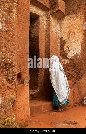 Ethiopian orthodox woman praying at the doorstep of the rock-hewn church Biete Gabriel-Rufael, UNESCO World Cultural Heritage site Lalibela, Ethiopia Stock Photo