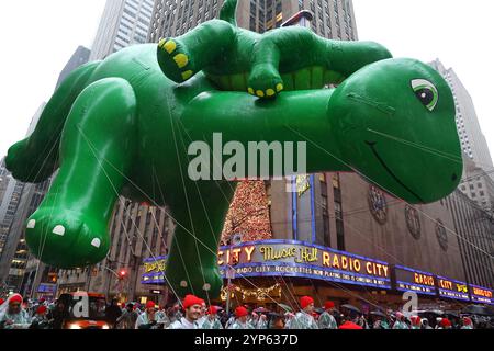 The Sinclair Oil balloon heads down Sixth Avenue during The 98th Macy's Thanksgiving Day Parade in New York, Thursday, Nov. 28, 2024. Baby DINO is a separate balloon & is attached to DINO’s back from several connection points. (Photo: Gordon Donovan) Stock Photo