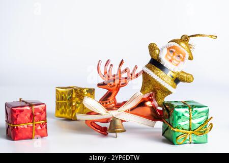 A cheerful display of Christmas decorations featuring a golden Santa statue, red reindeer and colorful gift boxes on a white background. Perfect for C Stock Photo