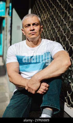 A man with a tattoo on his arm sits on a bench Stock Photo