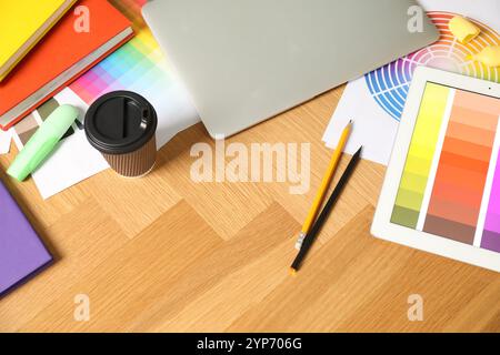 Designer's workplace with laptop, tablet, palettes and stationery on wooden table, above view Stock Photo