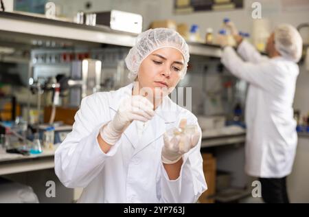 Concentrated young woman scientist doing experiment with petri dish Stock Photo