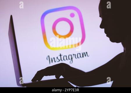 In this photo illustration, the Instagram logo is seen in the background of a silhouette of a person using a notebook Stock Photo