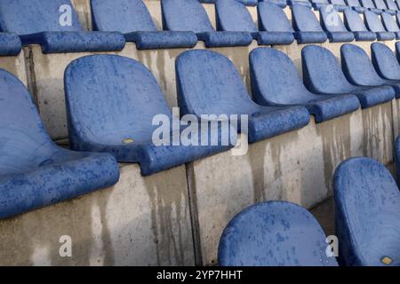 Empty wet blue stadium seats arranged in orderly rows Stock Photo