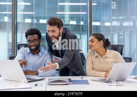 Diverse business team collaborating on project in modern office. Group of professionals using laptops, discussing strategy. Emphasizes teamwork, collaboration, technology, innovation, success Stock Photo