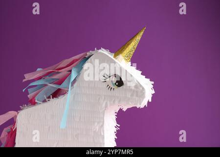 Bright pinata in shape of unicorn on purple background Stock Photo