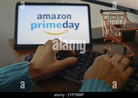 In this photo illustration, a person typing and in the background the Amazon Prime Day logo is displayed on the screen of a tablet Stock Photo