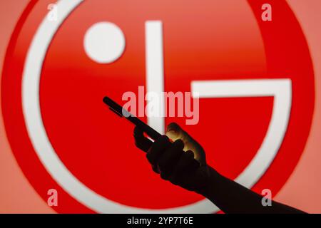 In this photo illustration the LG logo seen in the background of a silhouette woman holding a mobile phone Stock Photo