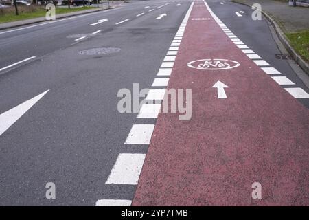 Red bike lane with directional arrows adjacent to a road in an urban setting Stock Photo