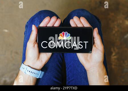 In this photo illustration, the Comcast Corporation logo is displayed on a smartphone screen Stock Photo