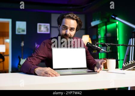 Portrait of man in studio filming tech tutorial on how to do maintenance on broken mockup laptop. Online show host teaching subscribers how to open and fix defective isolated screen notebook Stock Photo