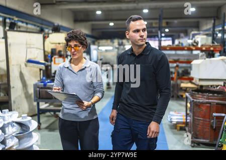 Female manager and male manual worker inspecting a cnc factory walking together and talking Stock Photo
