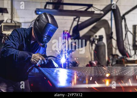 Unrecognizable man with safety goggles and gloves working in a factory welding pieces of metal Stock Photo