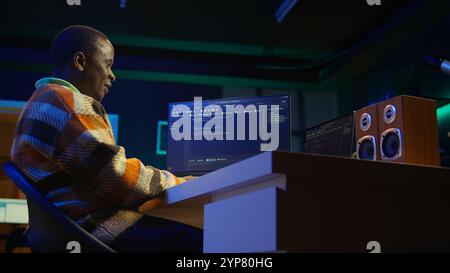 Black software engineer writes complex binary code scripts on computer, cybersecurity. Teleworking IT specialist in home office using programming language to safeguard consumer data. Camera B. Stock Photo