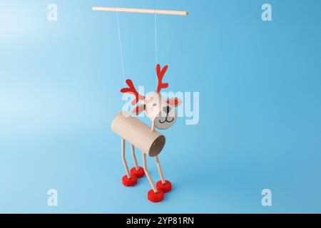 DIY reindeer puppet made from cardboard tubes, red bottle caps, and paper details. Festive paper craft marionette with red antlers. Holiday decoration Stock Photo