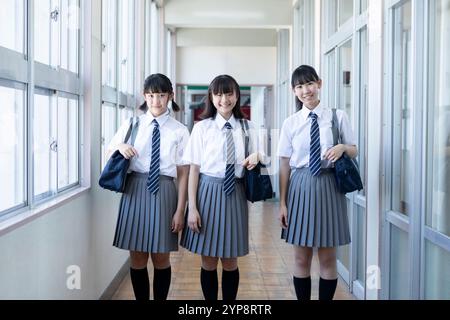 Junior high school students walking side by side down corridor Stock Photo