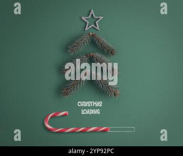 Christmas Loading Concept - Christmas Tree from fir tree twigs and Candy Cane on green paper background Stock Photo