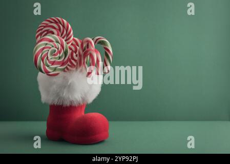 Christmas candy canes and  lollipops in Santa Claus boot on green background Stock Photo
