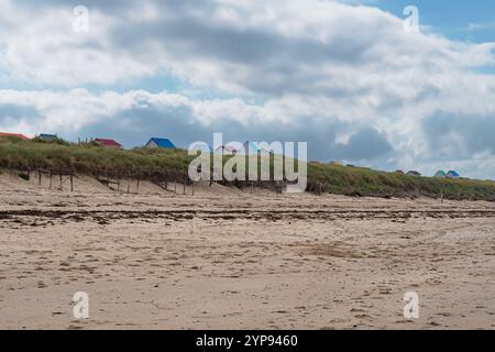 Beach huts with colourful roofs on the beach and dunes at Gouville-sur-Mer in Normandy, France Stock Photo