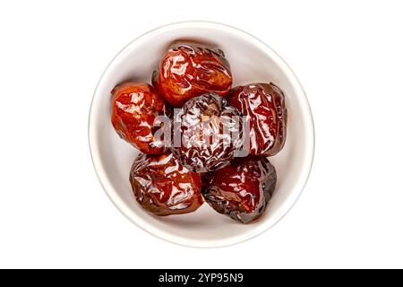 Top view pile of sweet pitted chinese jujube fruit preserved in syrup in white ceramic bowl isolated on white background with clipping path Stock Photo