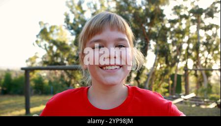 Happy girl standing with hands on hip in boot camp during obstacle course Stock Photo