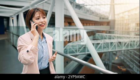 Japanese, business and woman with phone call in office of civil engineering, infrastructure and schedule. Engineer, mobile and communication of Stock Photo