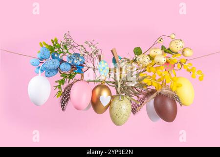 Creative bright spring Easter holiday concept. Painted Easter eggs, spring flowers, leaves and decorations hang on clothesline, bright sunny light cop Stock Photo