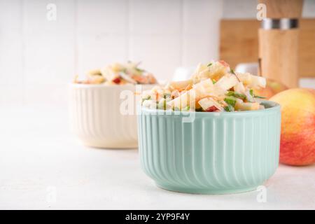 Asian Apple Slaw Salad with Apples, cabbage, carrot and spring onions. Healthy fall vegetable salad with yogurt dressing, in portioned bowls on kitche Stock Photo