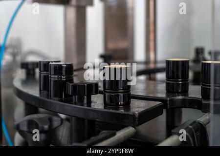 Detail shot of bottle cap alignment mechanism in automated olive oil bottling facility. Modern industrial food processing equipment with selective foc Stock Photo