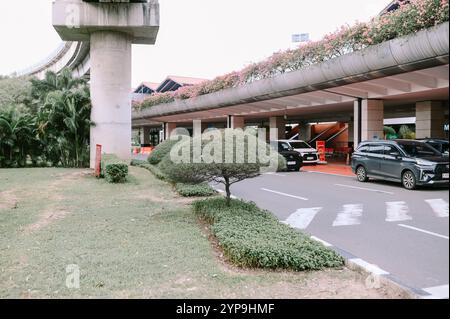 Bogor, November 18, 2024. Airport entrance filled with people exiting cars, ready to board their flight, with luggage in hand and a busy, bustling atm Stock Photo