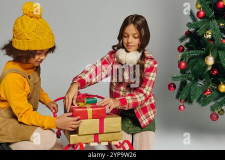 Two girls excitedly exchange beautifully wrapped presents during a joyful Christmas gathering. Stock Photo