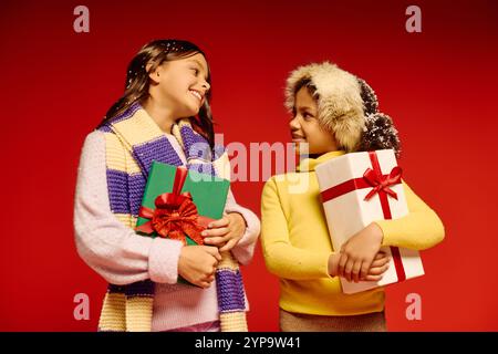 Two joyful girls share smiles and holiday gifts, embodying the spirit of Christmas 2025. Stock Photo