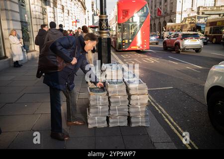 Stacks of evening newspapers stand on the street along Piccadilly, central London, England, UK Stock Photo