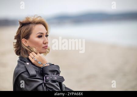 Young woman looking forward by the sea in a windy weather Stock Photo